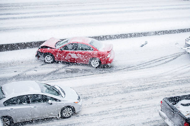 A red car has slid on the icy road and his into the freeway medium. This has created a traffic jam for the other cars.