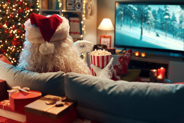 Happy Santa Claus relaxing on the couch at home and watching movies on TV